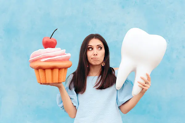 Woman holding large cupcake and tooth