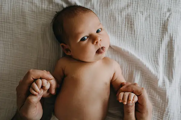 A newborn baby making a cute face with their tongue sticking out.
