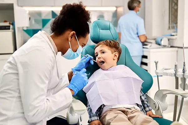 Little boy in dental chair smiling with Dentist